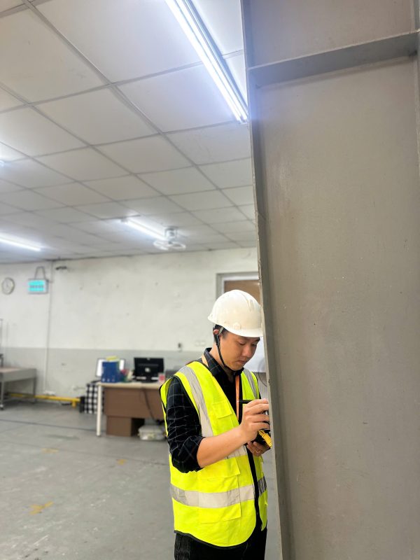 Kỹ sư kiểm định đang kiểm tra hiện trạng cột bê tông trong nhà xưởng đang hoạt động.