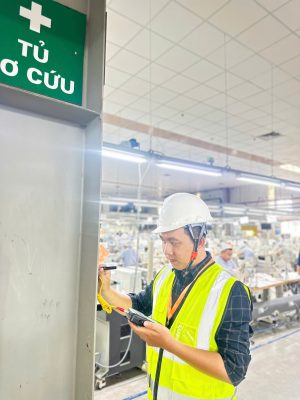 Kỹ sư kiểm định kiểm tra hiện trạng kết cấu cột trong nhà xưởng đang vận hành sản xuất.