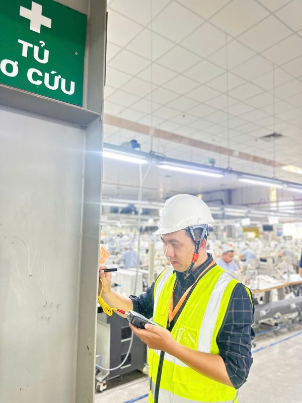 Kỹ sư kiểm định kiểm tra hiện trạng kết cấu cột trong nhà xưởng đang vận hành sản xuất.