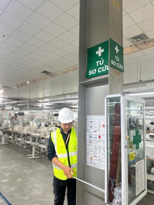 Kỹ sư kiểm định kiểm tra tủ sơ cứu và lối thoát hiểm trong nhà xưởng sản xuất.