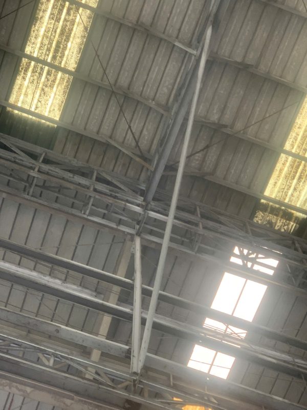 Hiện trạng kết cấu mái thép nhà xưởng công nghiệp tại khu vực giáp tường và hệ khung trong quá trình kiểm định an toàn chịu lực.