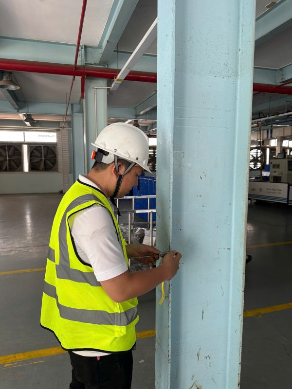 Kỹ sư kiểm định đo đạc và kiểm tra kích thước cột nhà xưởng tại hiện trường.
