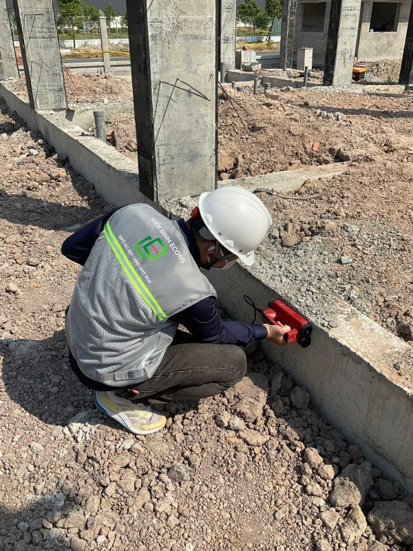 Kỹ sư kiểm định thực hiện kiểm tra hiện trạng kết cấu nền móng và cột bê tông trong kiểm định định kỳ công trình.