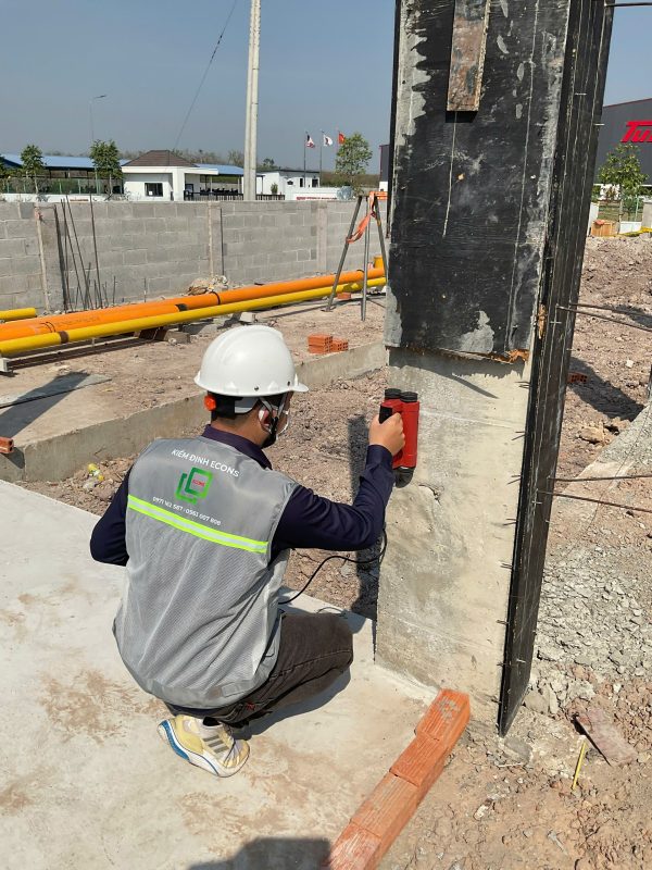 Kỹ sư kiểm định thực hiện kiểm tra hiện trạng nền móng và cấu kiện bê tông ngoài hiện trường trong kiểm định định kỳ công trình.