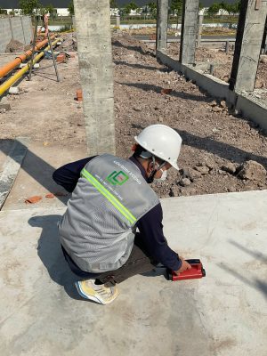 Kỹ sư kiểm định đo đạc và kiểm tra hiện trạng nền móng công trình trong quá trình kiểm định định kỳ.