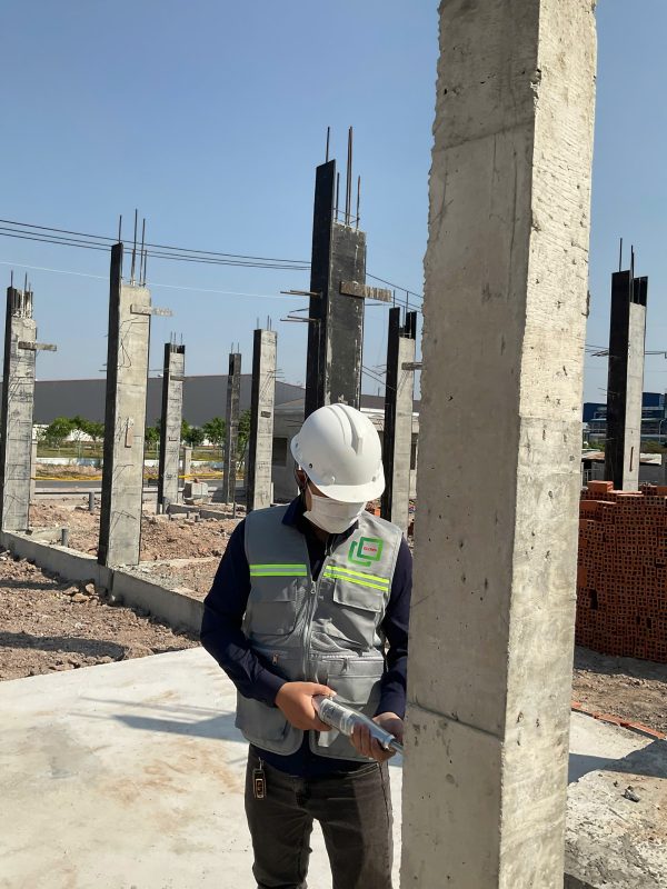 Kỹ sư kiểm định đo kiểm độ thẳng đứng và cao độ cột bê tông tại công trình xây dựng.