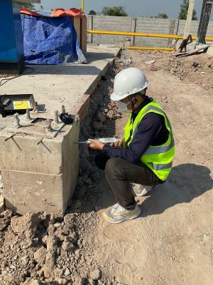 Kỹ sư kiểm định khảo sát nền và khu vực móng nhà xưởng tại hiện trường.