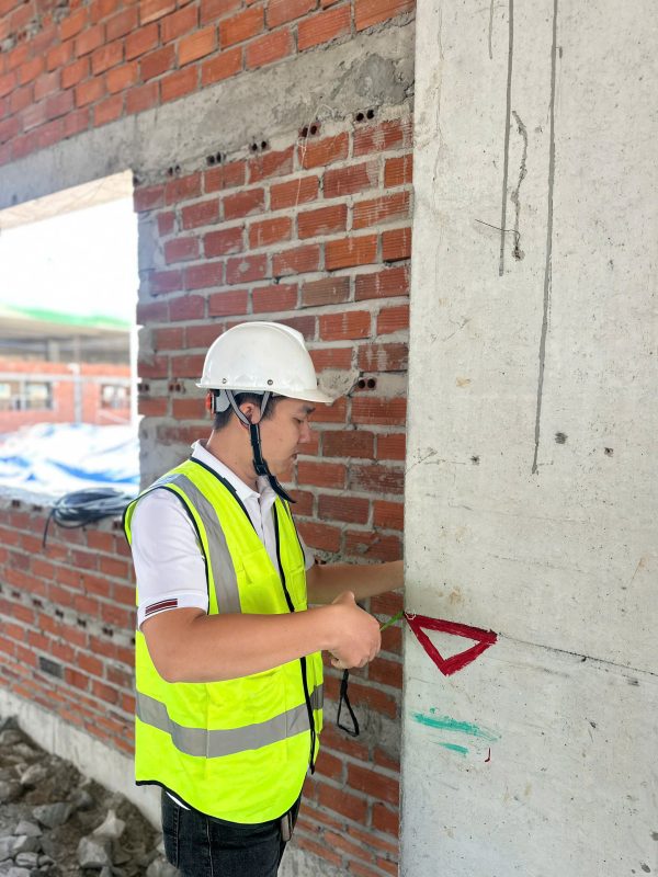 Đo kiểm kích thước và độ vuông góc cột bê tông trong quá trình kiểm định nhà xưởng.