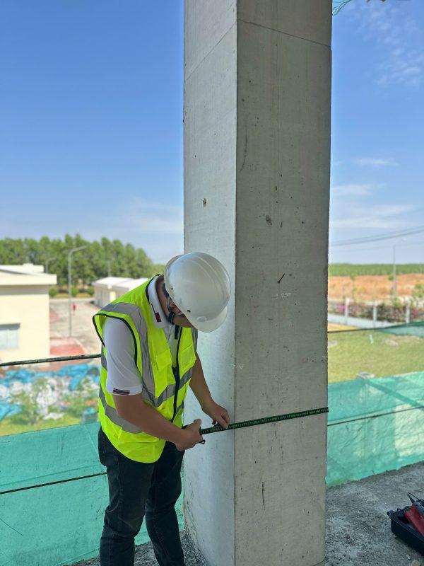 Kỹ sư kiểm định đo kích thước hình học cột bê tông bằng thước thép tại công trình.