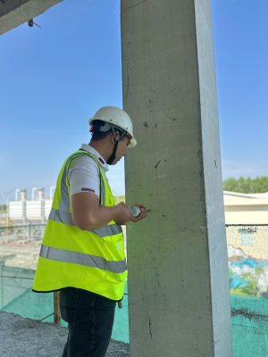 Kỹ sư kiểm định đo kích thước hình học cột bê tông tại công trình nhà xưởng.