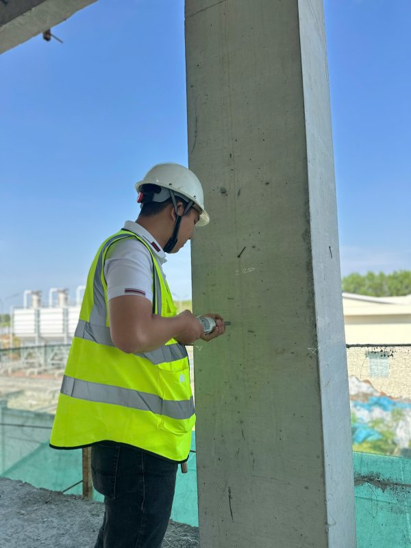 Kỹ sư kiểm định đo kích thước hình học cột bê tông tại công trình nhà xưởng.