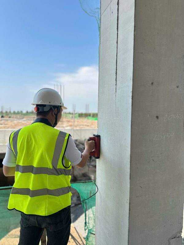 Kỹ sư kiểm định sử dụng máy dò thép kiểm tra cốt thép trong cột bê tông nhà xưởng.
